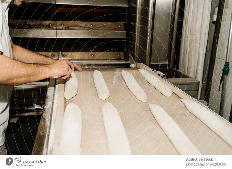 Crop baker preparing bread on tray in bakery prepare dough cut raw natural man similar professional equipment work process ingredient product soft tender