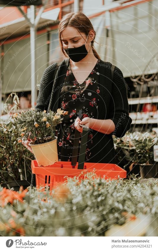young woman buying flowers for the garden beautiful blossom care caucasian centre cheerful choice choosing chose closeup colorful commercial coronavirus