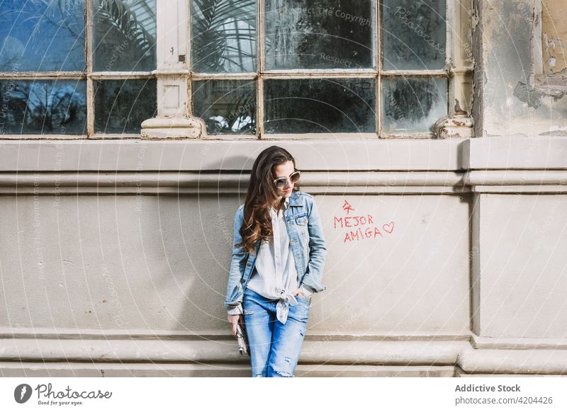 Stylish woman standing near old building in city style denim jeans outfit urban shabby trendy female sunglasses confident street modern cool contemporary cloth