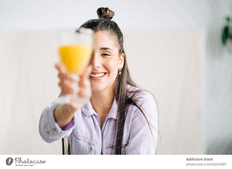 Happy woman with delicious orange juice in house glass cover eye cheerful beverage candid enjoy home portrait outstretch smile glad sincere toothy smile