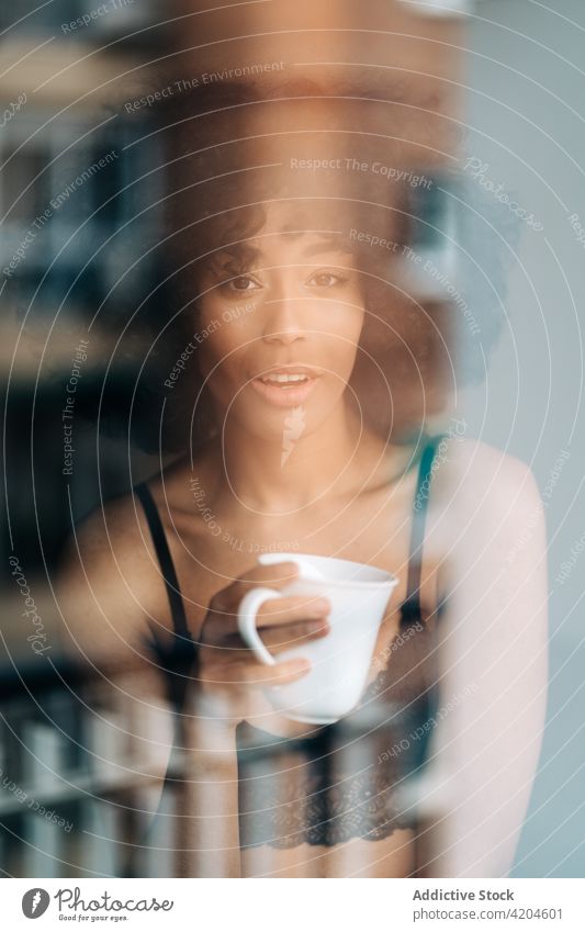 Black woman with cup of drink looking at camera home tender lace top beverage afro harmony female ethnic black african american content coffee tea cheerful