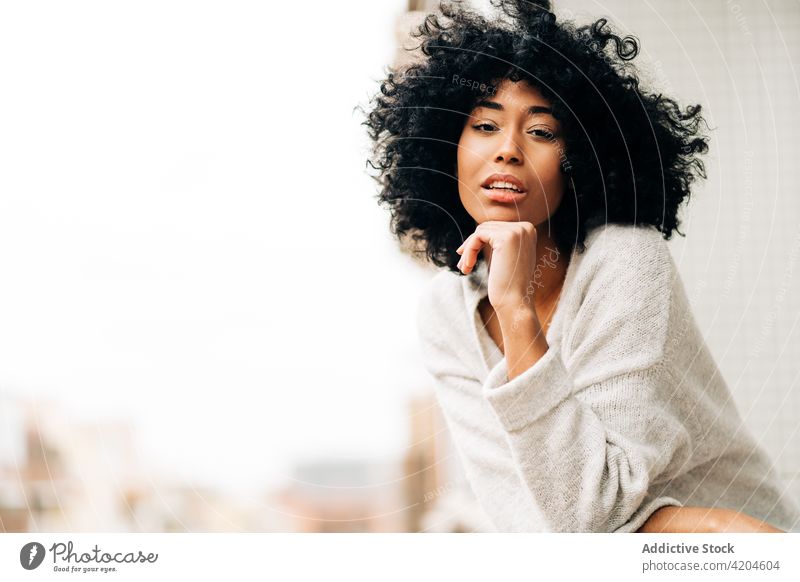 Serene black woman standing on balcony serene terrace dreamy tranquil afro appearance hairstyle peaceful female ethnic african american lean railing daydream