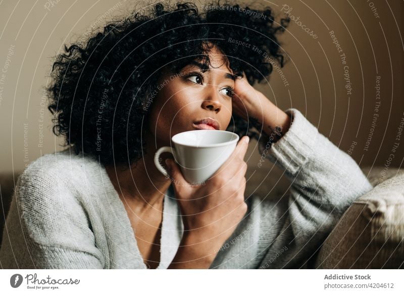Thoughtful black woman with cup of drink looking away thoughtful contemplate beverage home alone melancholy lonely ponder female ethnic african american mug