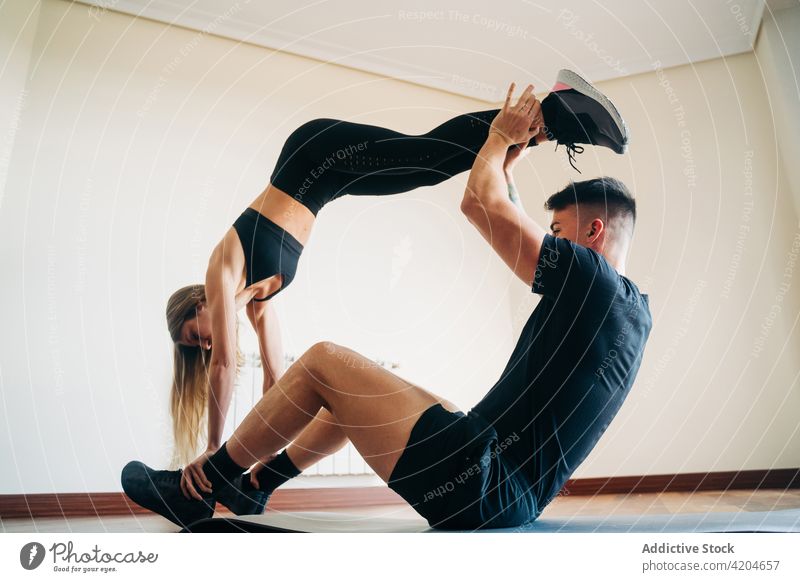 Flexible couple doing acroyoga exercise acro yoga workout balance fitness training practice gymnastic acrobatic support woman activewear athlete room mat