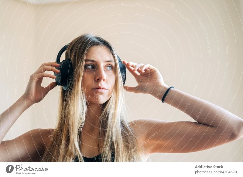 Calm woman in headphones in room music listen song melody hand near head hobby meloman dynamic sound lady female long hair light serious focus concentrate