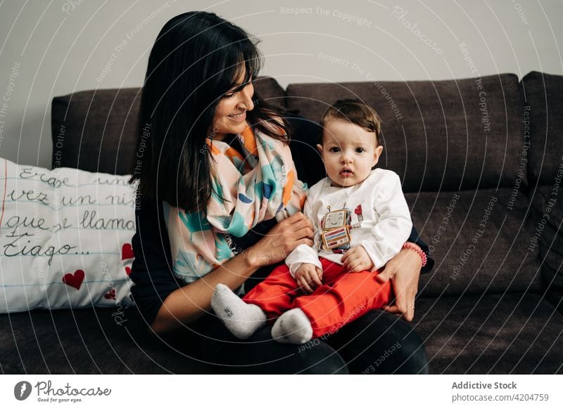 Multiethnic young mother with adorable little son on couch woman child sofa smile joy together love spend time happy toddler multiethnic multiracial diverse