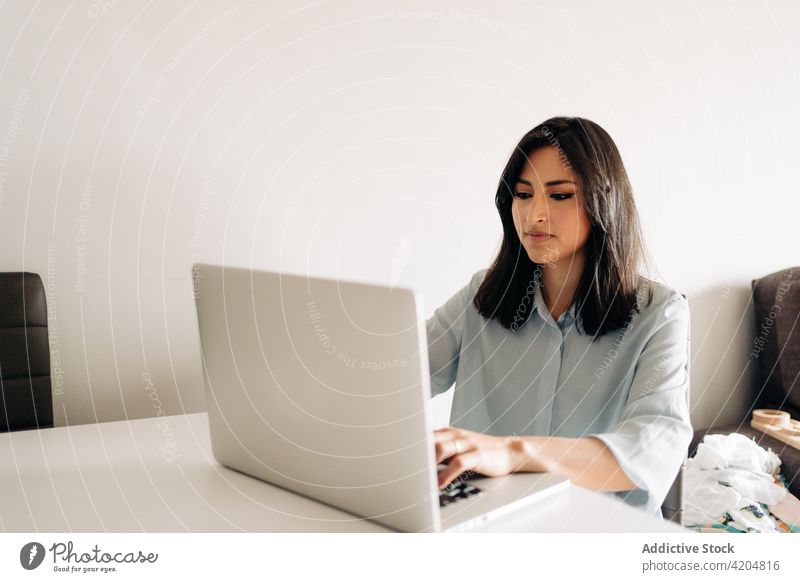Concentrated young woman working on laptop from home using remote concentrate at home freelance formal workspace browsing business occupation entrepreneur