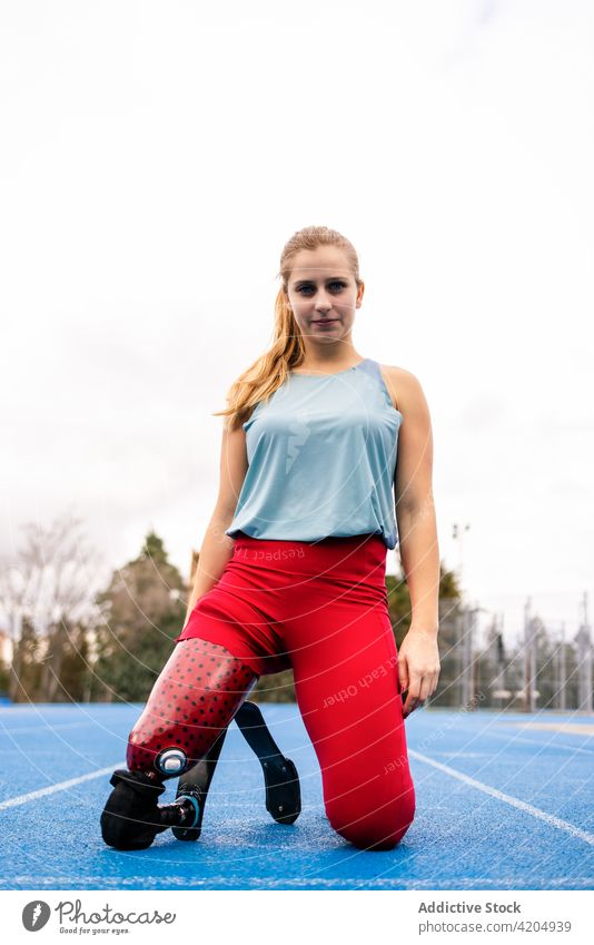 Content sportswoman with bionic leg prosthesis at stadium athlete runner paralympic artificial limb female professional fit amputee track and field disable