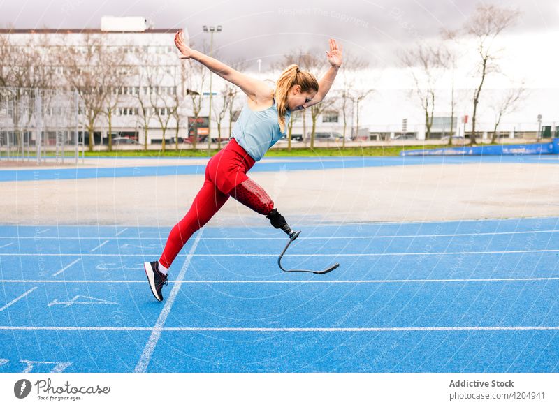 Energetic sportswoman with leg prosthesis running at stadium runner paralympic athlete training energy sprinter female bionic professional racetrack artificial