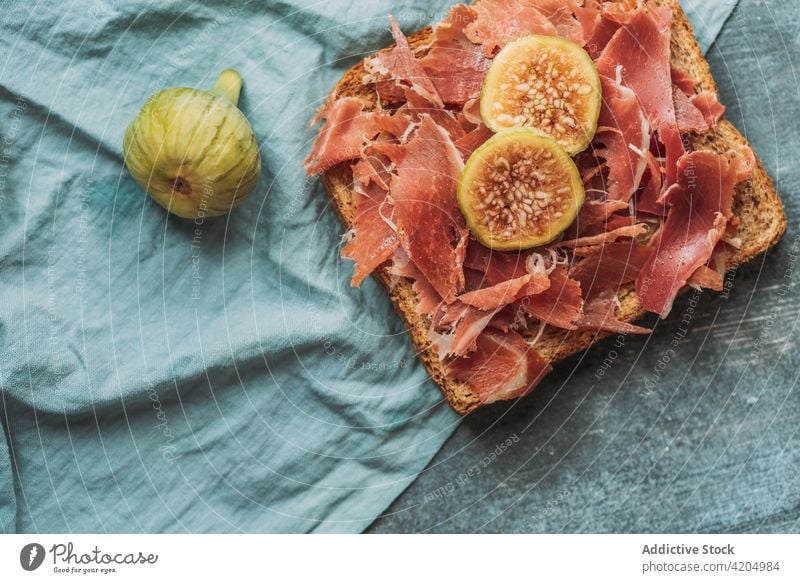 Delicious toast of Iberico ham, cheese and fresh figs on the blue tablecloth iberic appetizer bruschetta gourmet snack sandwich healthy meat prosciutto food