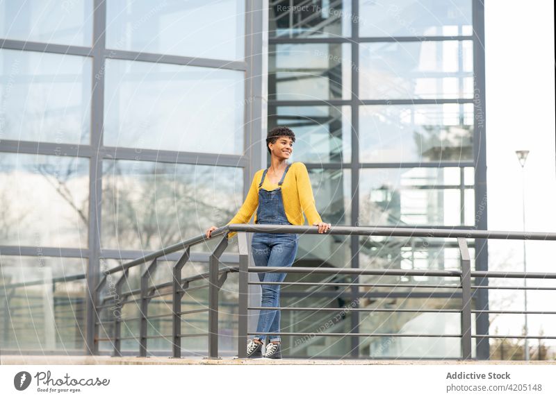 Smiling black woman standing near modern building in city urban trendy outfit style glass wall cheerful cool female ethnic african american smile street