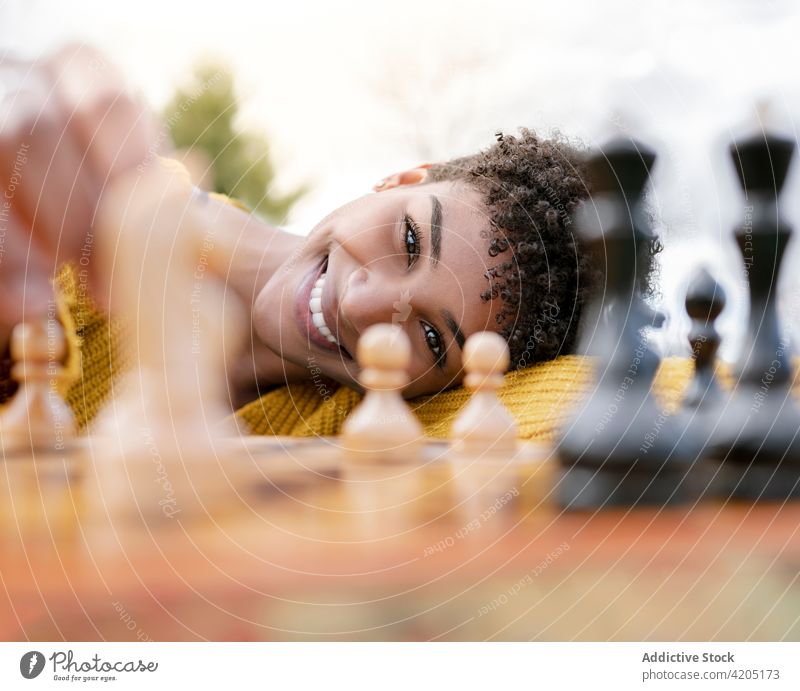 Black woman playing chess in park cheerful piece game intellect board game smile female ethnic black african american positive table glad joy young lady happy