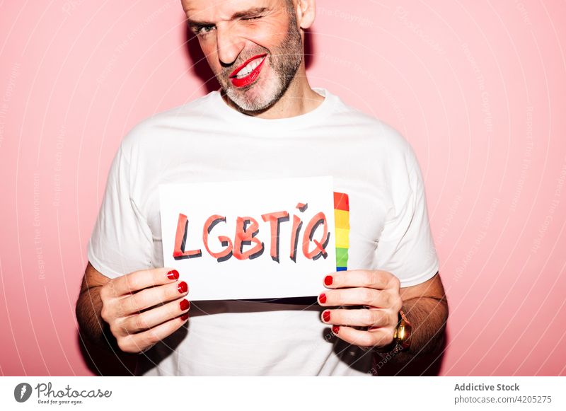 Positive gay showing paper with LGBTIQ inscription in pink studio man homosexual lgbtiq pride queer grimace concept demonstrate support activism male adult
