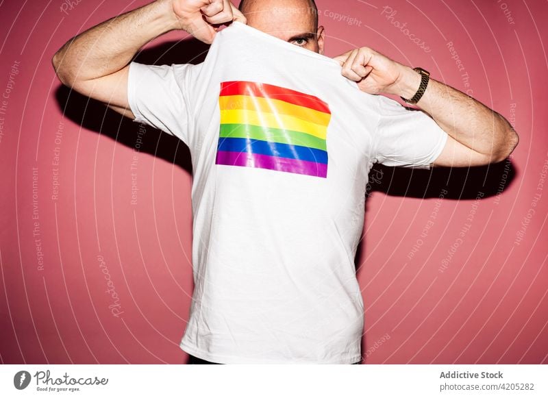 Unrecognizable gay demonstrating t shirt with LGBT flag man cover face lgbt homosexual equal tolerance demonstrate concept pride liberty gender male young