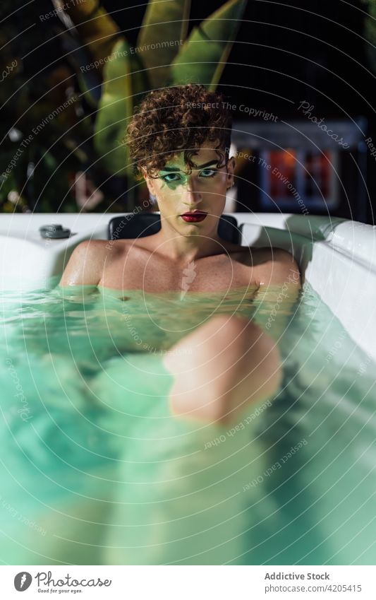 Sensual gay with makeup resting in hot tub man transsexual sensual nail individuality unusual dusk mindfulness water ripple enjoy lgbtq shorts extravagant