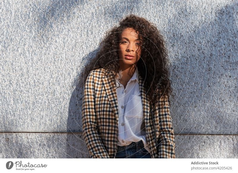 Calm black woman leaning on concrete wall pensive street confident calm urban city ponder thoughtful focus female african american trendy style young appearance