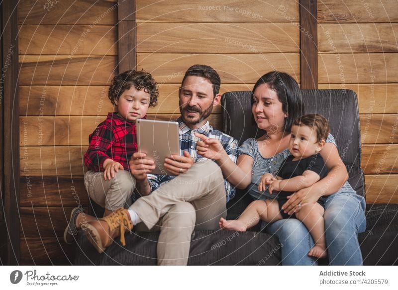 Cheerful family using tablet together at home watch video cheerful children entertain weekend gadget device parent online couch couple kid love relationship