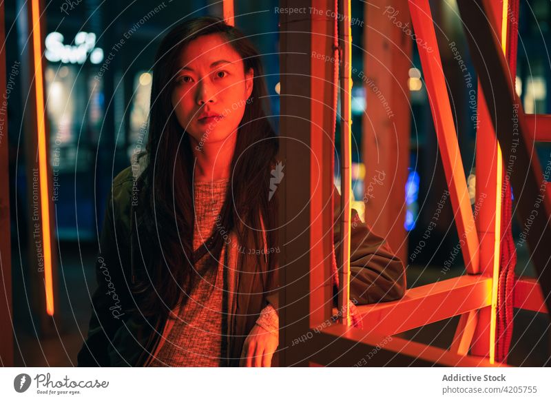 Portrait of Asian girl posing near to red neon light on the street asian asian girl calm casual chill chinese city cityscape confident copy space evening