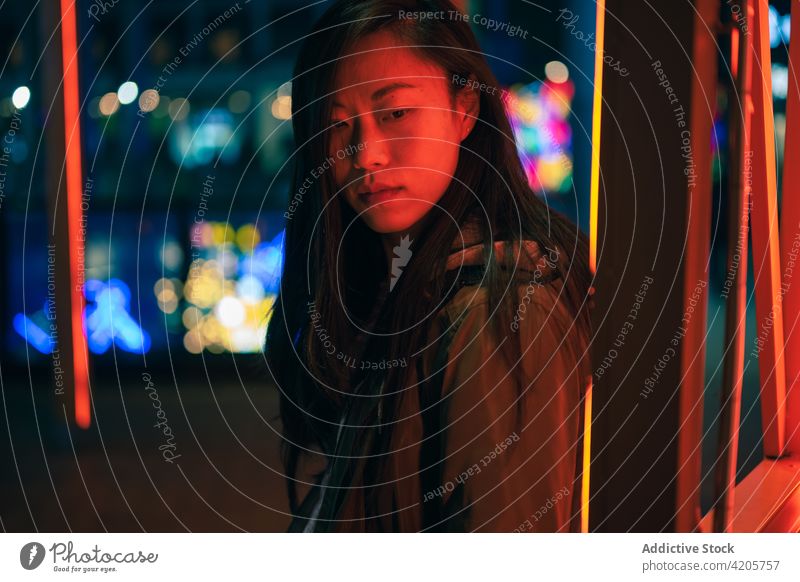 Portrait of Asian girl posing near to red neon light on the street asian asian girl calm casual chill chinese city cityscape confident copy space evening