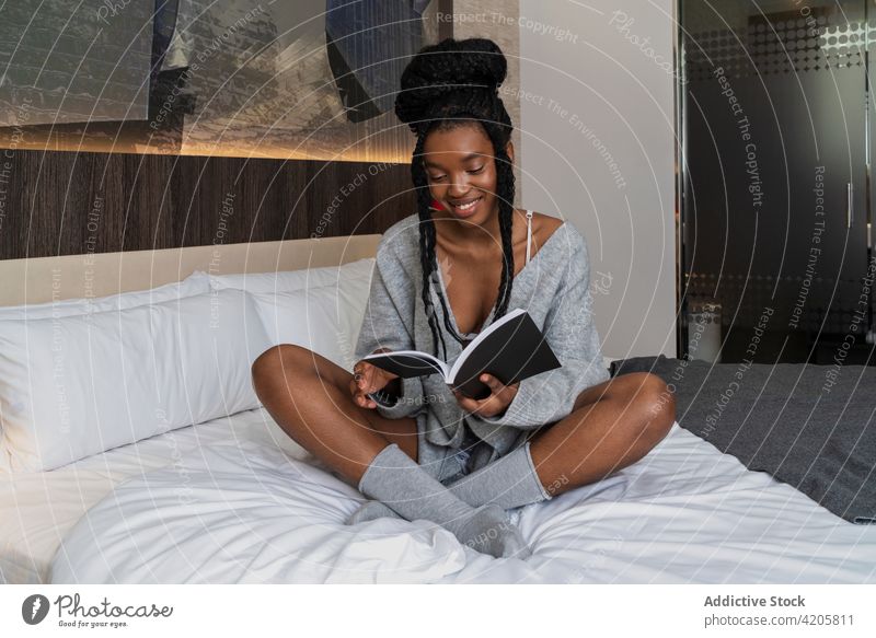 Content young black lady reading notes while lying on bed woman book student education knowledge assignment happy smile positive female african american ethnic