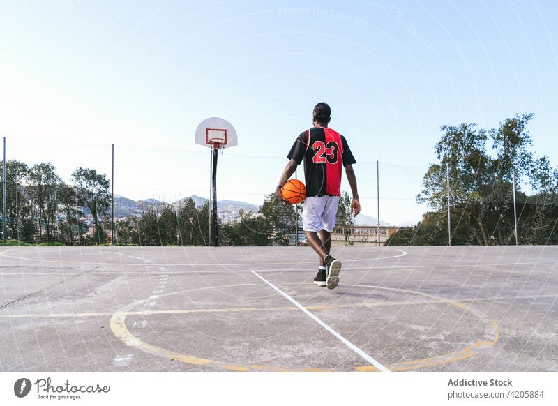 Anonymous confident black basketball player on sports ground streetball man playground determine court athlete male ethnic african american uniform muscular