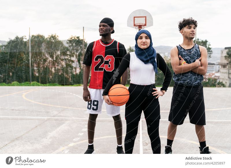 Diverse streetball players standing together on basketball court team sports ground determine multiethnic multiracial diverse black african american muslim