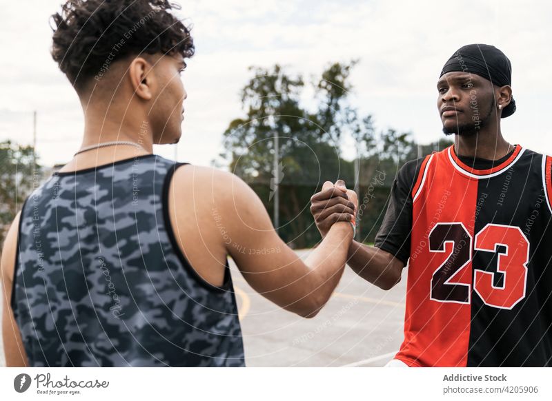 Black male basketball players shaking hands on court handshake men greeting gesture streetball playground together ethnic black african american game athlete