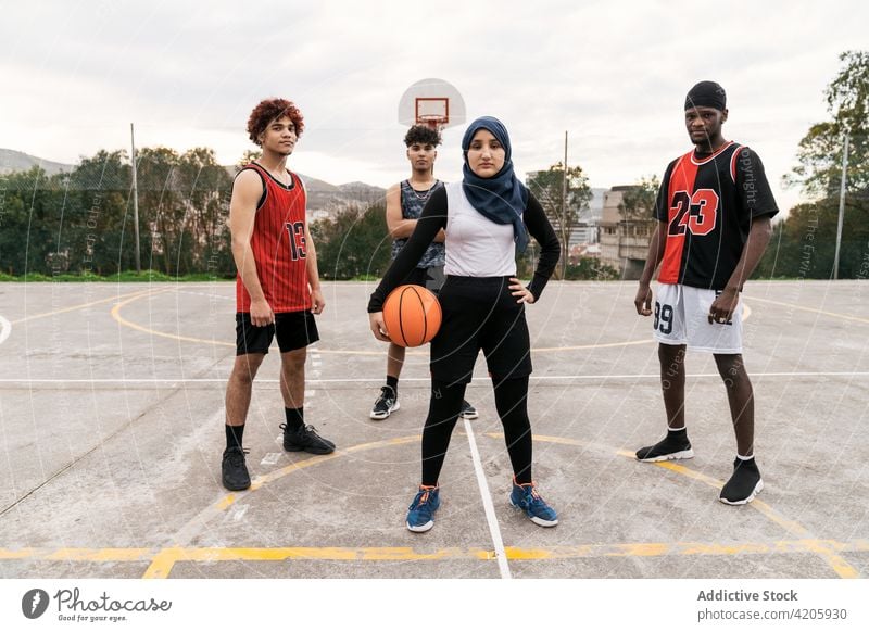 Diverse streetball players standing together on basketball court team sports ground determine multiethnic multiracial diverse black african american muslim