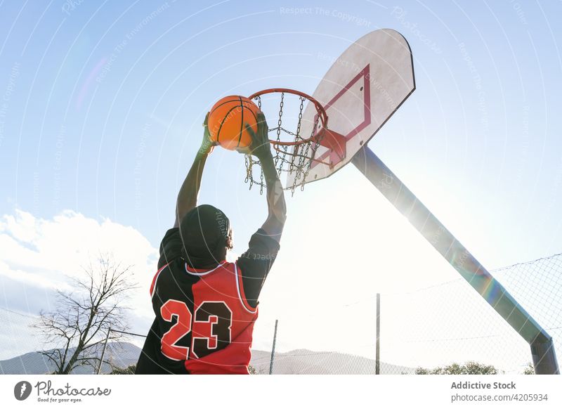 Black basketball player jumping with ball on playground score man streetball hoop sportsman moment energy male ethnic black african american athlete game power