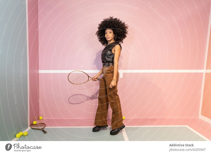Black woman with tennis racket in studio player court posture fashion trendy style female afro confident personality individuality stand appearance hobby