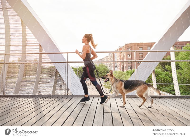 Sporty female running with dog on footbridge sportswoman german shepherd cardio active pet training fitness wellbeing athlete workout wellness activity friend