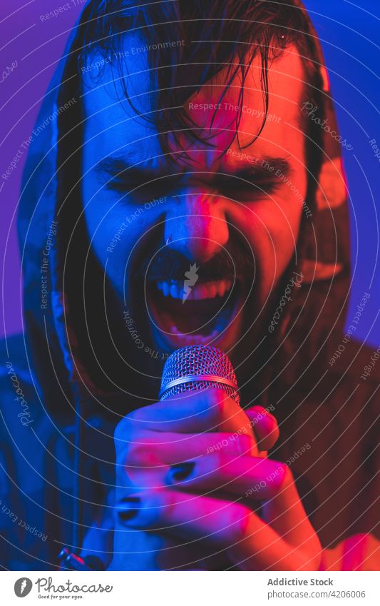 Brutal man singing with microphone in neon lights singer rock song hipster loud expressive perform music concert male adult illuminate sound entertain beard