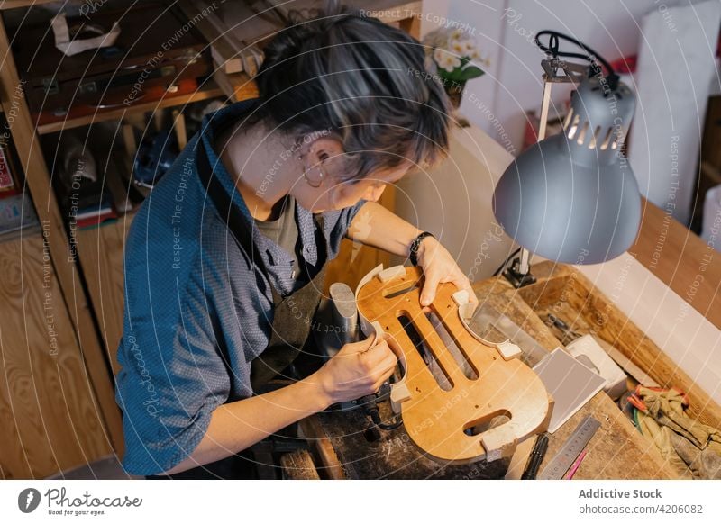 Craftswoman attaching violin body to workbench craftswoman workshop instrument professional art female table job hobby artisan studio talent occupation process
