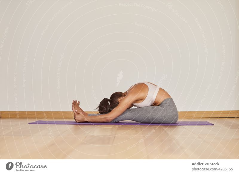 Anonymous woman showing Caterpillar pose on yoga mat caterpillar pose stretch flexible healthy lifestyle energy vitality wellness room forward bend talent skill