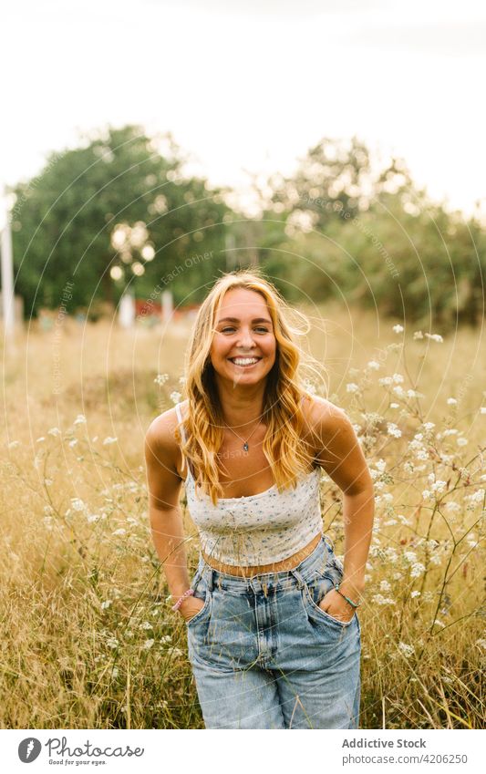 Cheerful stylish woman standing in field in summer cheerful enjoy meadow delight carefree weekend summertime female happy positive nature content smile outfit