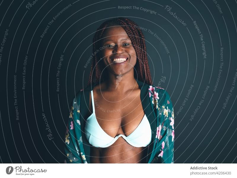Cheerful black woman in bra standing in studio cheerful lingerie gown underwear smile charming delight female ethnic african american positive style joy braid