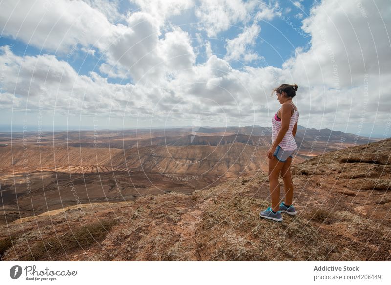 Woman standing on hilltop and admiring hilly landscape woman traveler hike highland valley nature rocky hiker casual mountain scenic spacious clear wanderlust