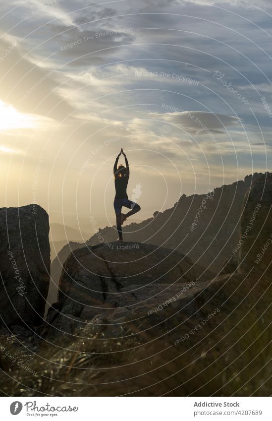 Woman performing Vrksasana on hilltop woman yoga tree with arms up pose recreation meditate nature flexible confident mountain vrksasana female tree posture