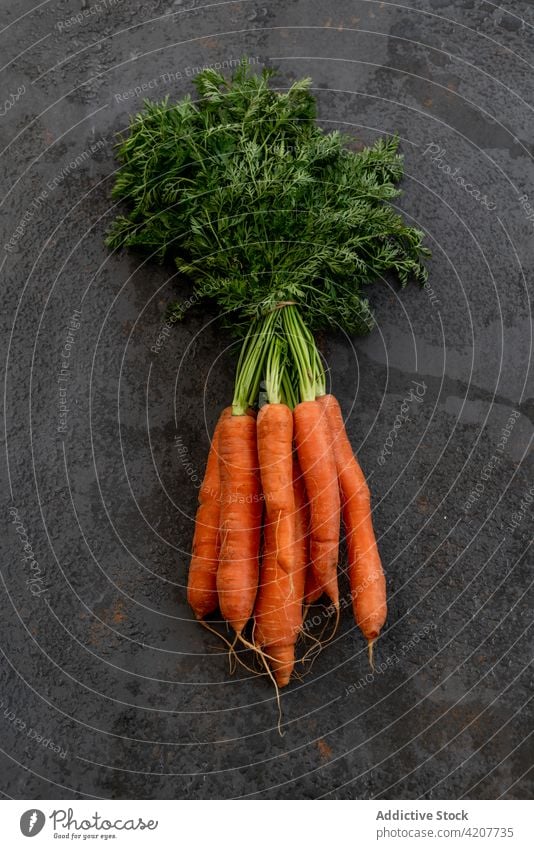 Bunch of fresh carrots on black table bunch vegetable ripe harvest vitamin food healthy organic natural edible nutrition shabby weathered grunge vegetarian raw