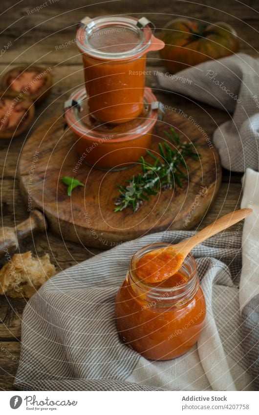 Glass pots with homemade fried tomato sauce on table handmade conserve fresh basil jar tasty condiment kitchen organic vegan culinary veggie healthy herb