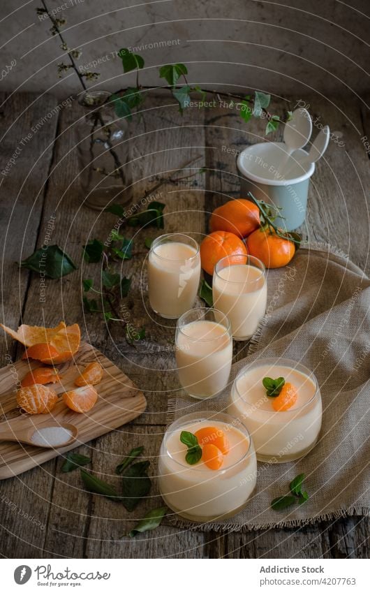 Sweet tangerine mousse in glasses on table dessert serve treat sweet ingredient citrus fruit wooden healthy tasty kitchen cup mint leaf garnish napkin delicious