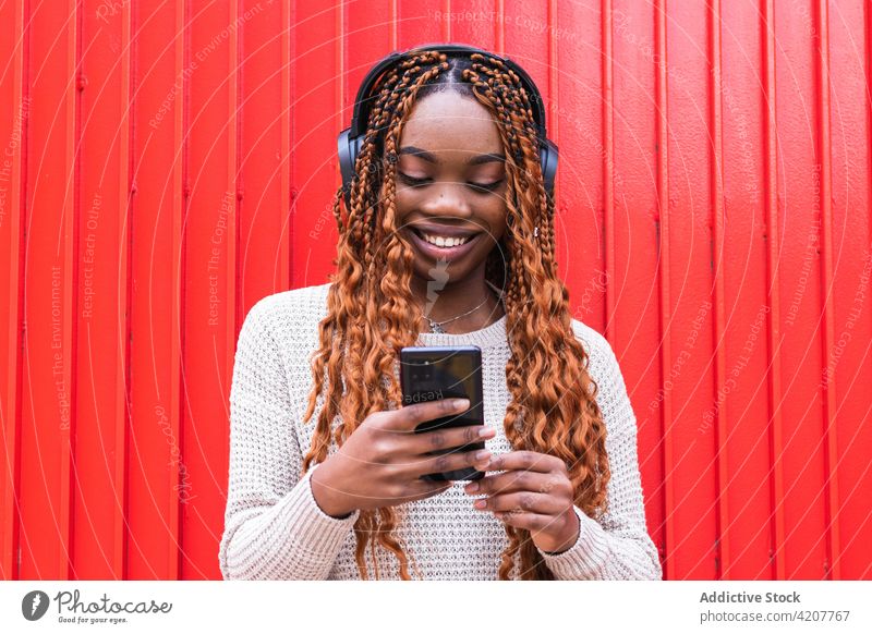 Delighted black woman listening to music in headphones enjoy carefree wireless song smile street female ethnic african american device audio eyes closed sound