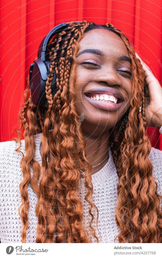 Delighted black woman listening to music in headphones enjoy carefree wireless song smile street female ethnic african american device audio eyes closed sound