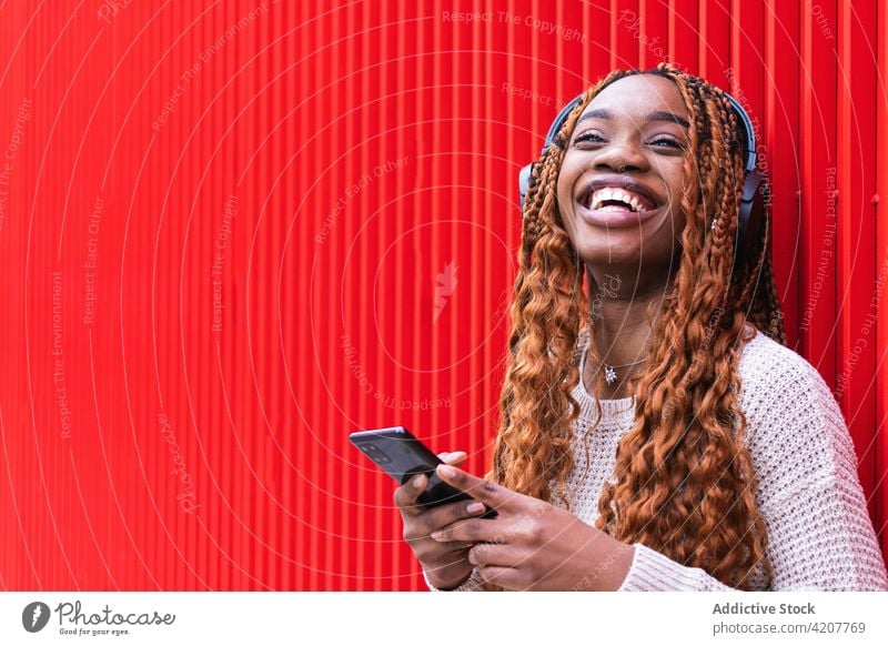Delighted black woman listening to music in headphones enjoy carefree wireless song smile street female ethnic african american device audio sound positive