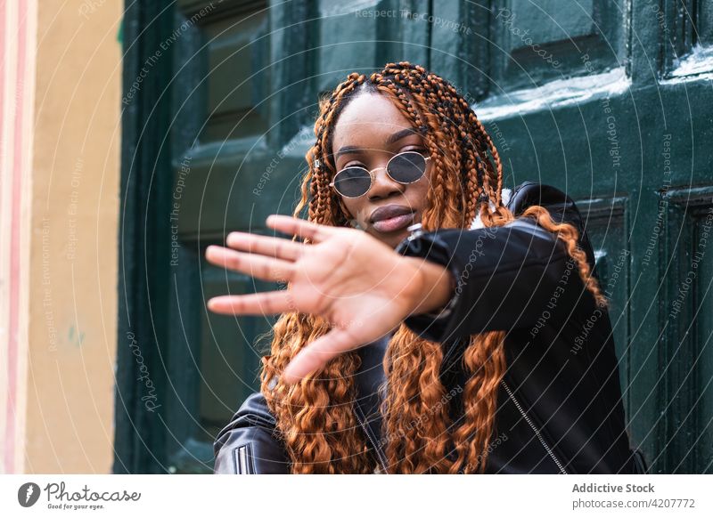 Stylish black woman covering face and looking at camera cool style street cover face confident trendy braid hairstyle outfit female ethnic african american