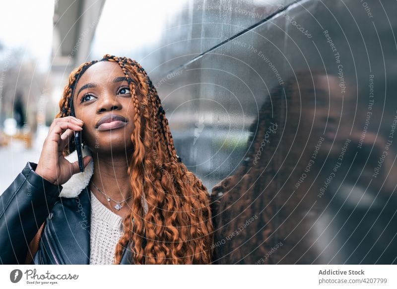 Stylish black woman making a phone call on smartphone on the street city style trendy outfit braid hairstyle female ethnic african american building lifestyle