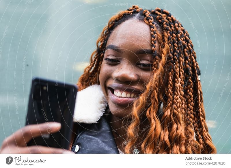 Stylish happy black woman using smartphone on street browsing city style cheerful trendy outfit braid hairstyle social media female ethnic african american