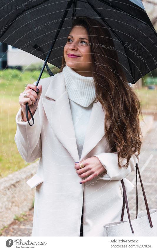 Happy stylish woman with umbrella walking in park fashion spring coat outfit style rain happy trendy female adult accessory lifestyle cheerful smile lady