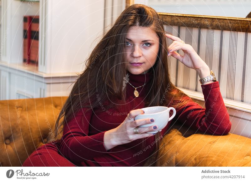 Woman with cup of coffee on the couch woman cafe dream window pensive happy drink charming dreamy female adult beverage relax free time lifestyle rest enjoy
