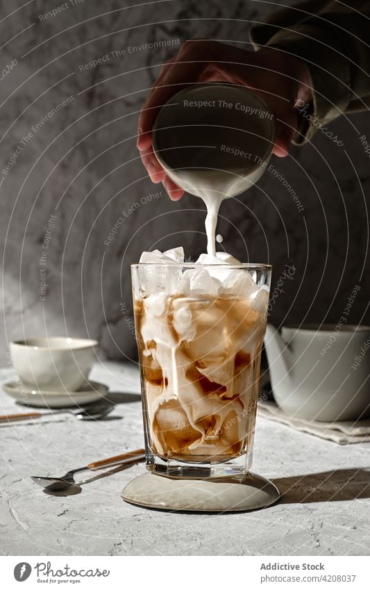 Iced coffee with milk in glass ice pour cold drink prepare beverage hand liquid delicious tasty caffeine sunlight aroma serve morning yummy energy portion